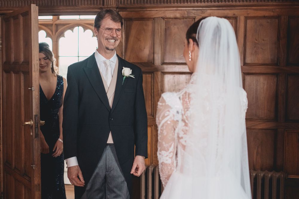 Wedding couple sharing first look moment in wood-paneled hallway at Ashridge House.