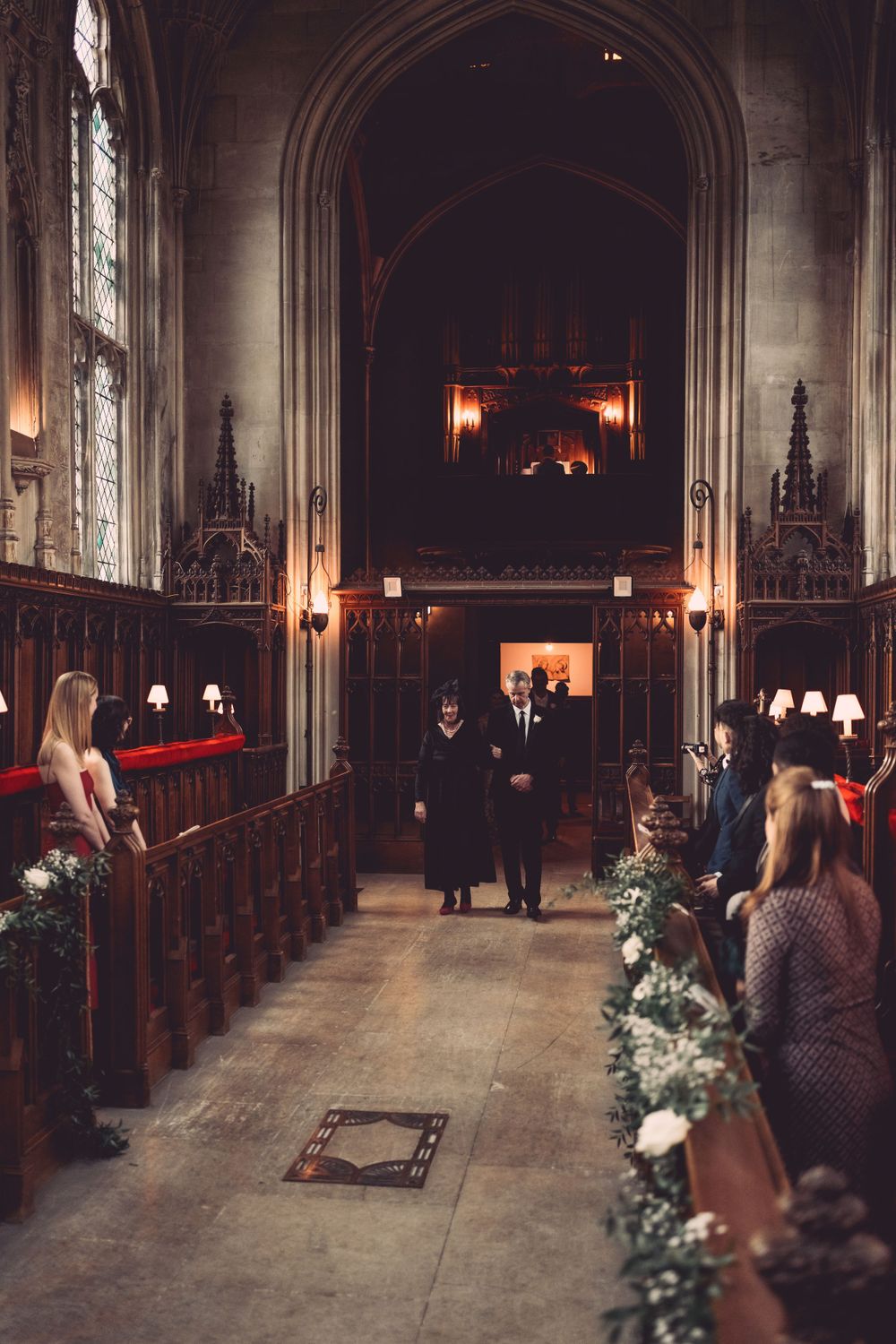 Gothic church aisle decorated with greenery and lined with wooden pews at Ashridge House.