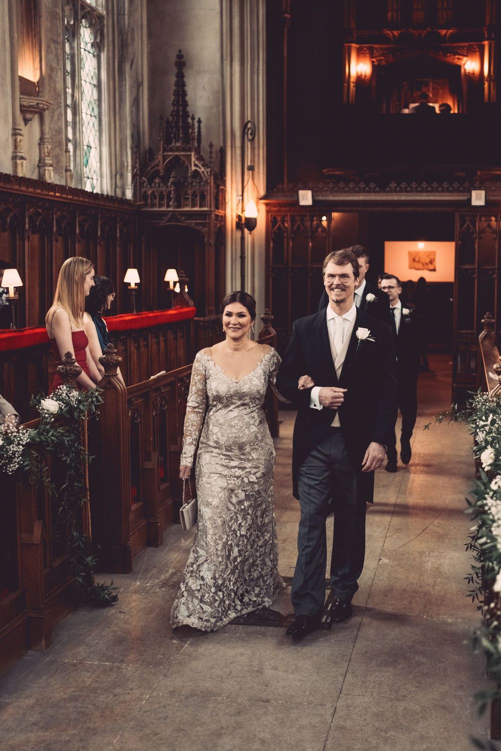 Couple walking down the church aisle after ceremony among candlelit decorations at Ashridge House.