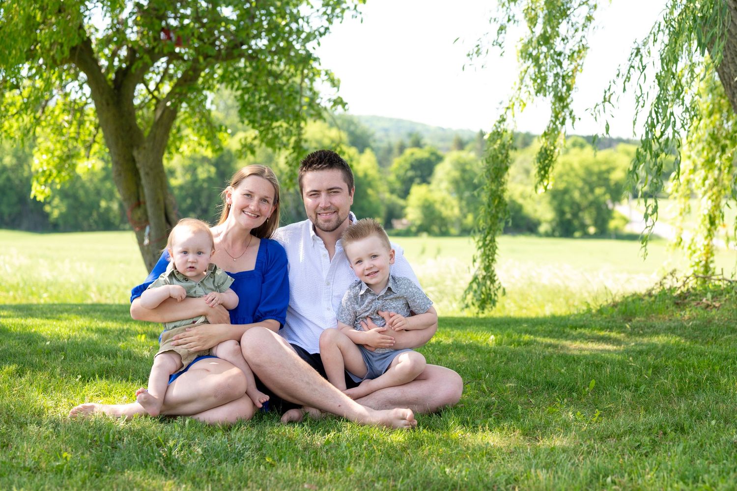 A family of three poses together in a wildflower meadow during golden hour.