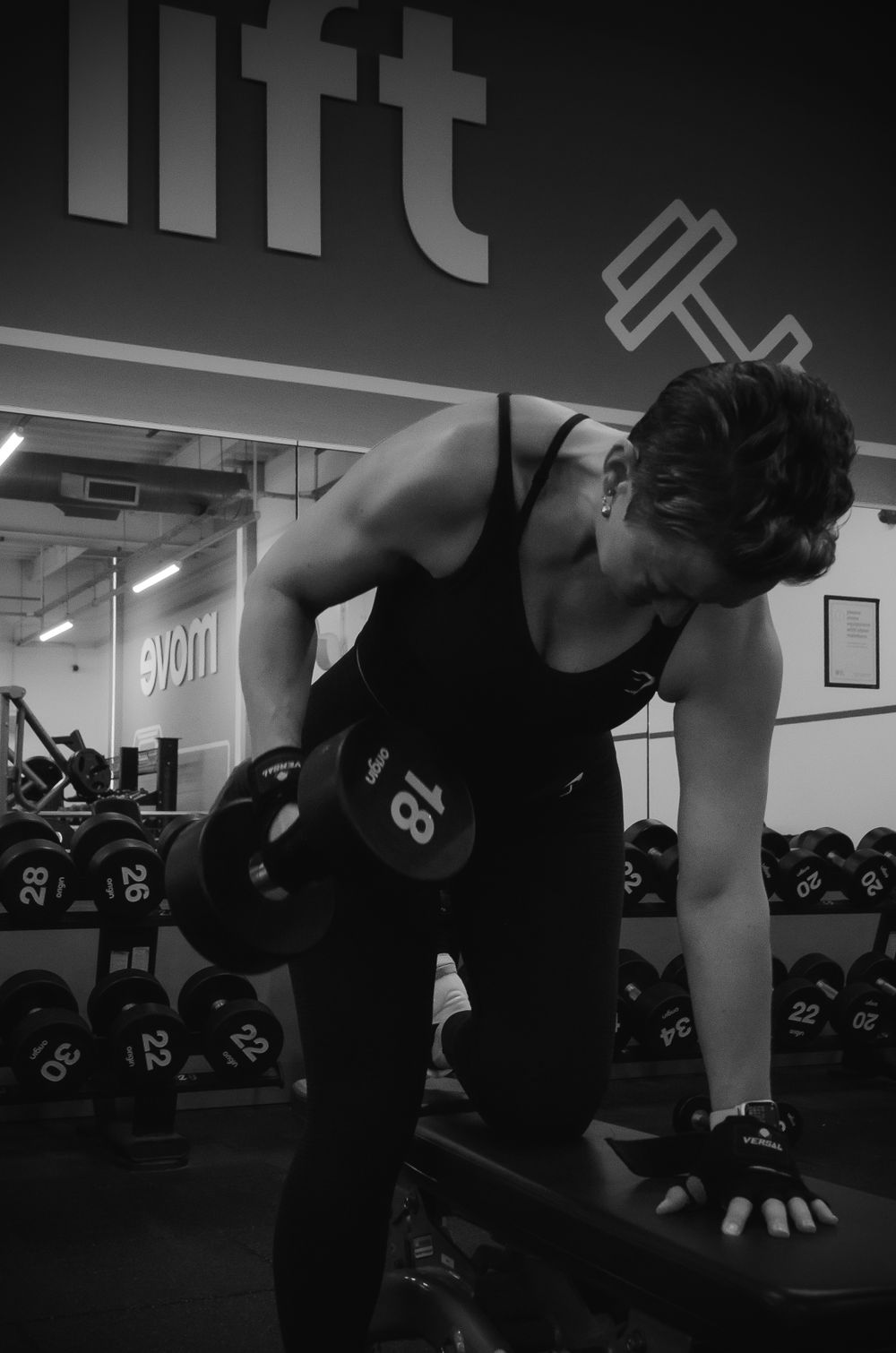 A person performs dumbbell rows during a workout at a fitness facility.
