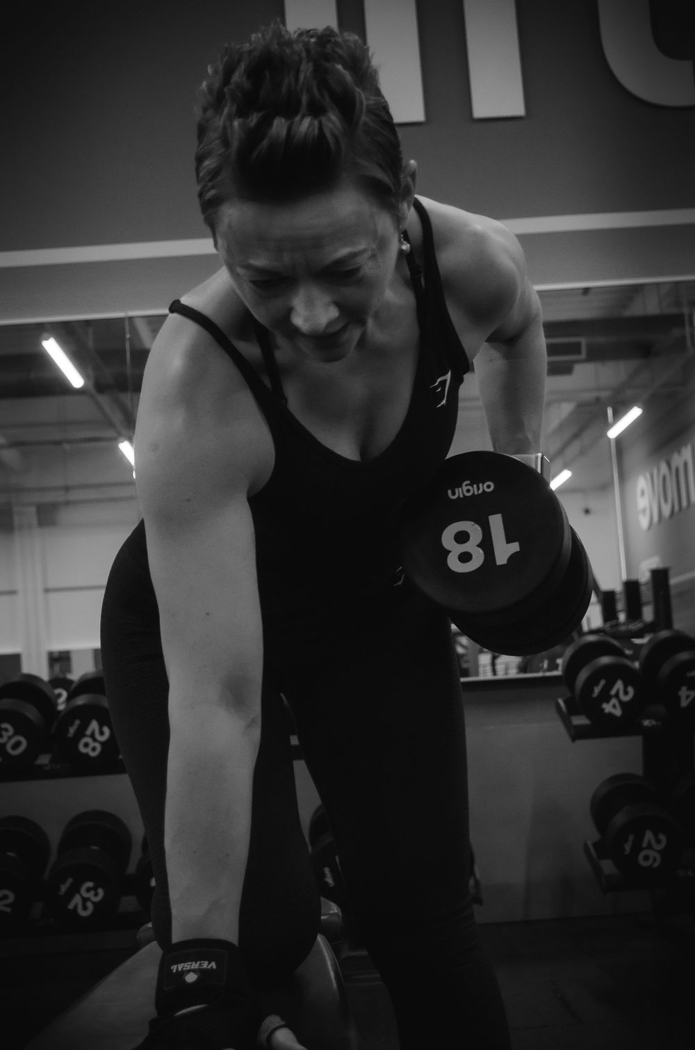 An athlete in black workout gear performs strength training exercises in a modern gym setting.