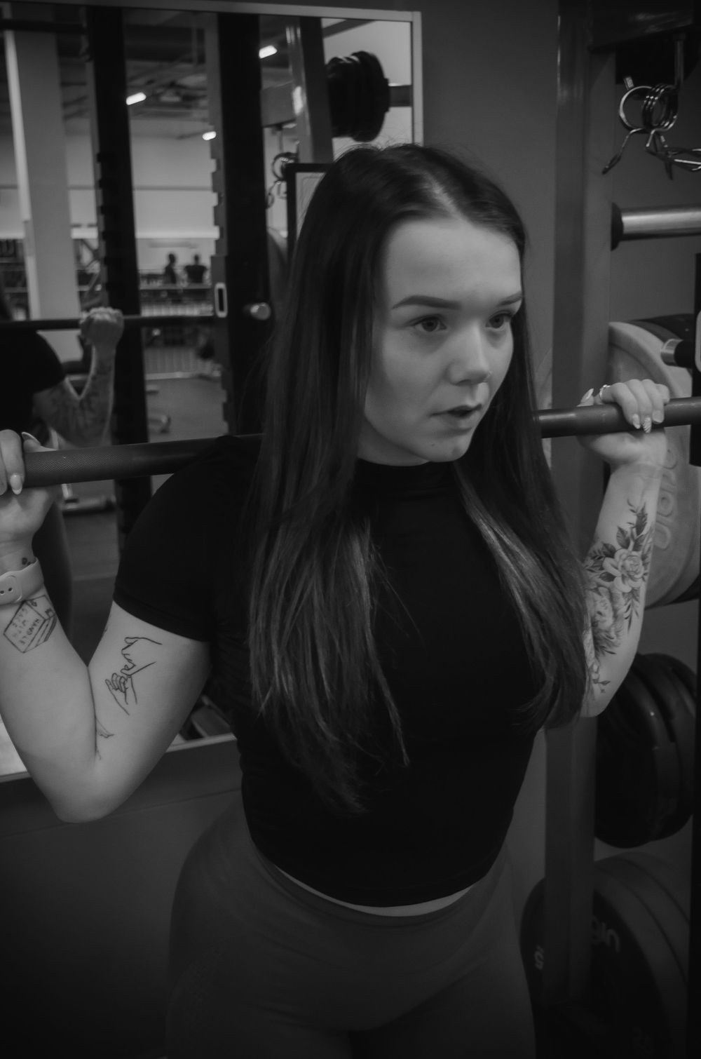 A person trains with weights at a gym wearing black athletic wear.