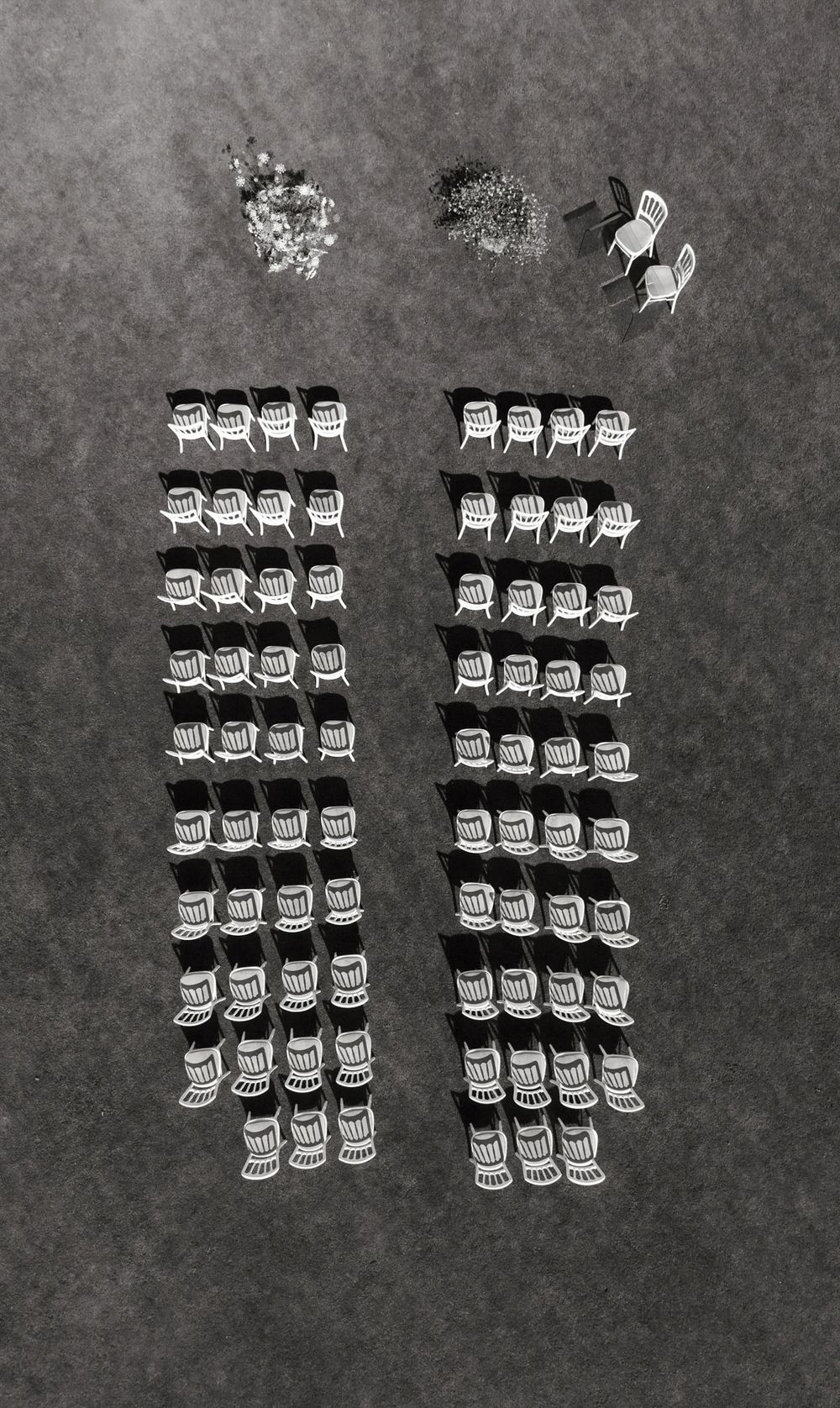 Aerial black and white view of rows of chairs arranged in two columns on an open ground.