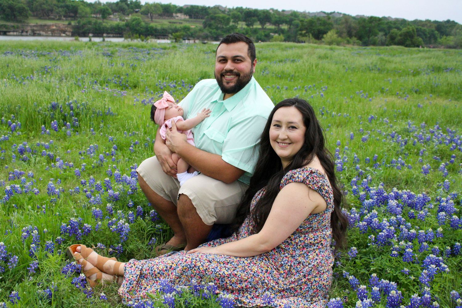 Family sitting in a field of vibrant blue wildflowers on a sunny spring day.