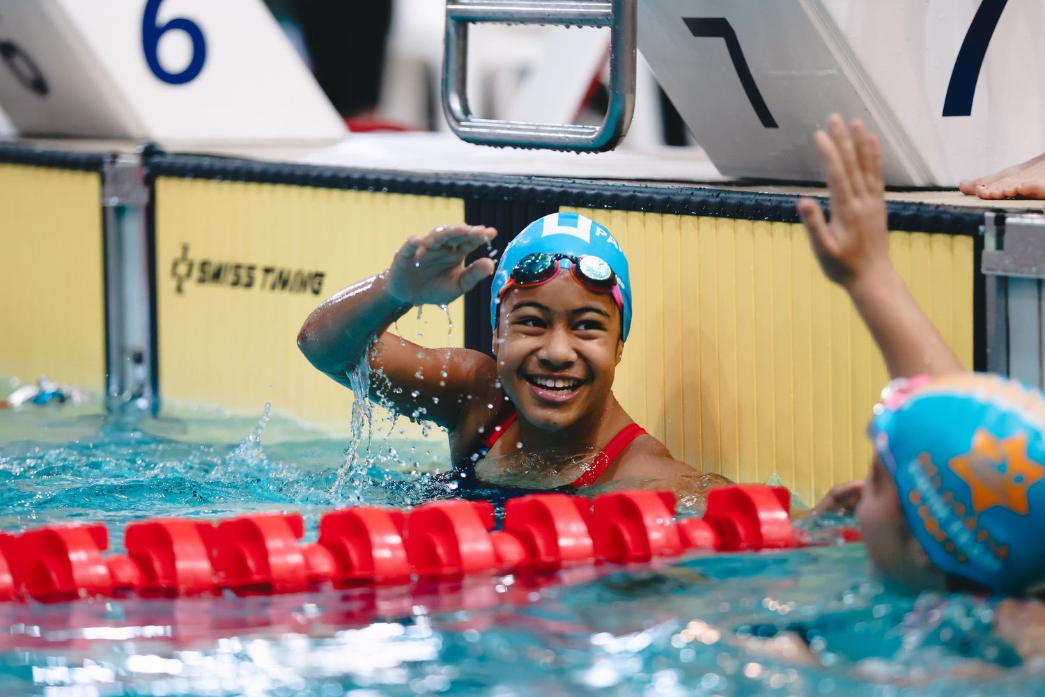 Competitive swimmer celebrating in pool lane with goggles and swim cap.