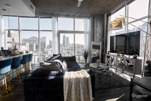 Luxury high-rise loft living room with floor-to-ceiling windows offering stunning city skyline views and elegant furnishings.