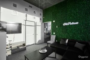 Contemporary lounge space featuring a lush green living wall with neon sign, black sofa, and sleek modern decor.