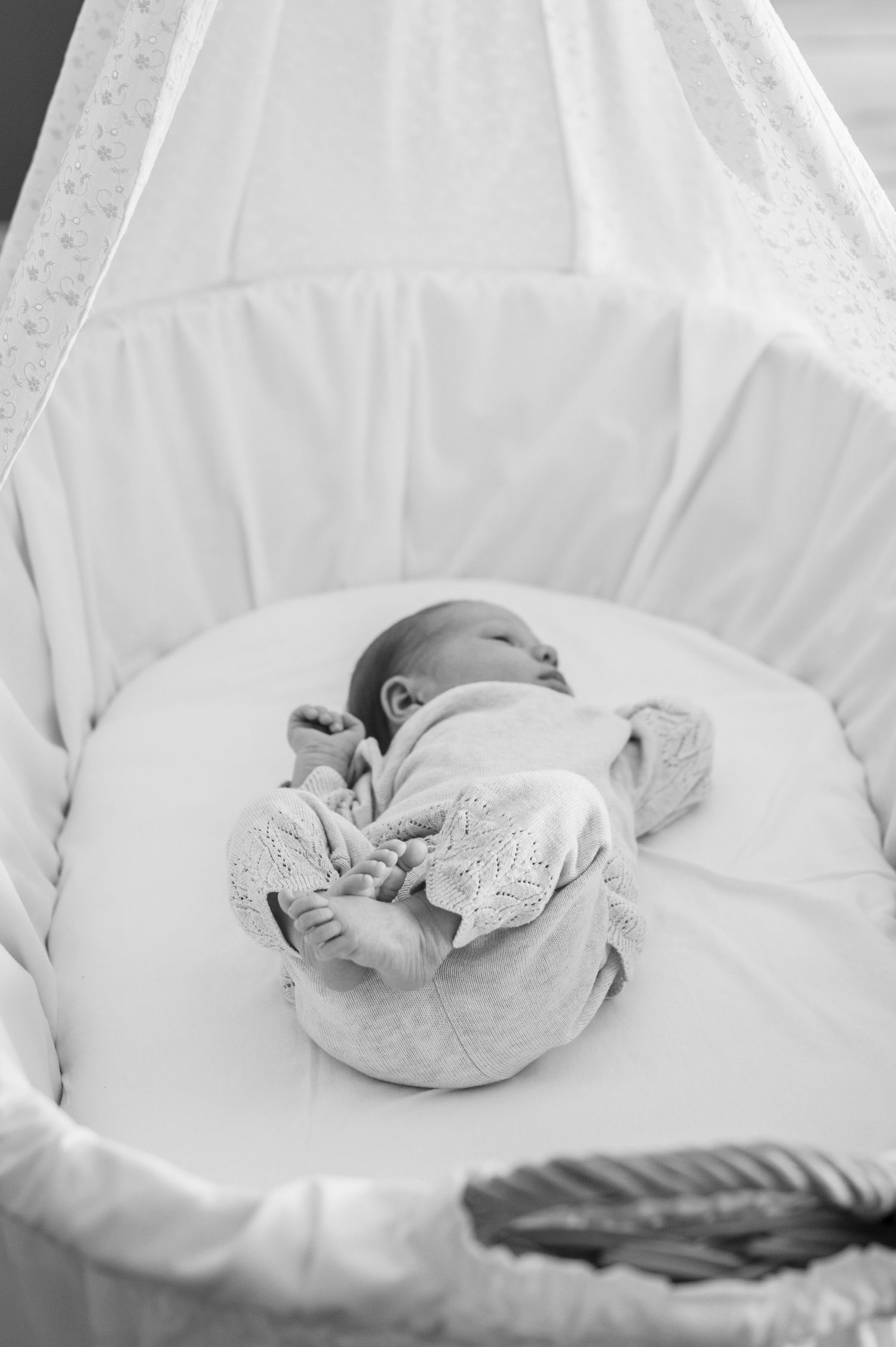 Ein schwarz-weiß Foto von einem Baby in einem Stubenwagen.