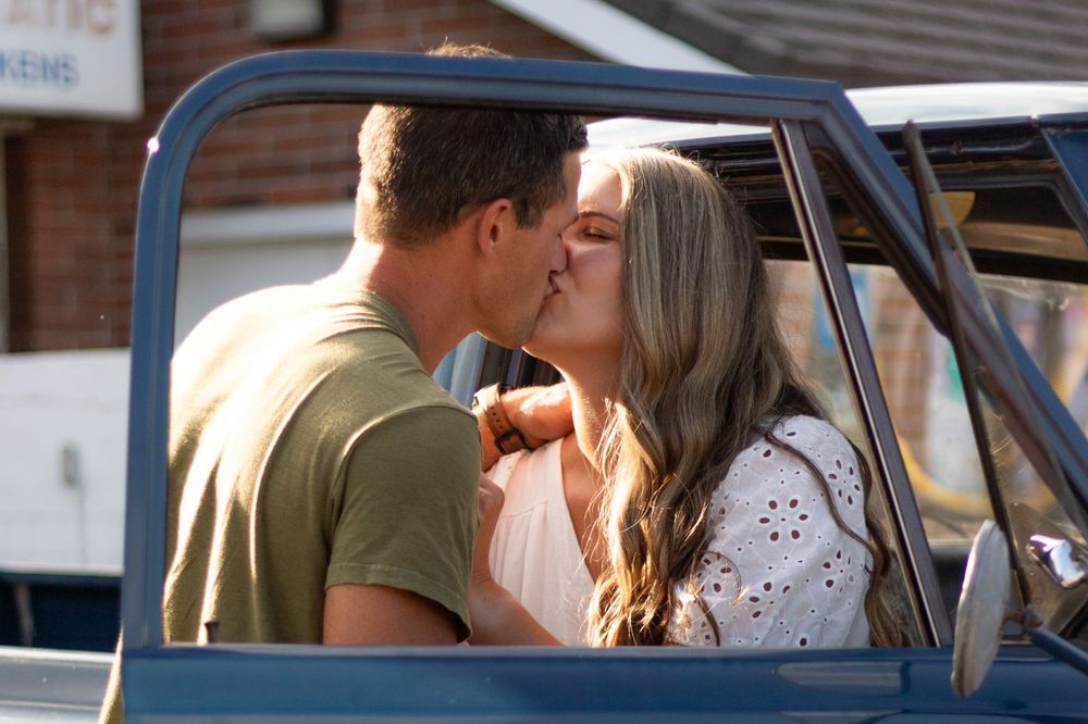 Romantic moment captured through vintage car window.