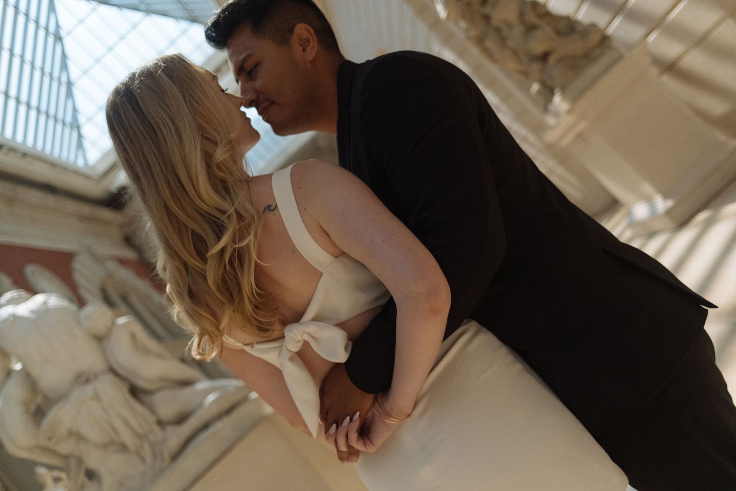 A romantic moment between a couple on a classic stone balcony with columns.