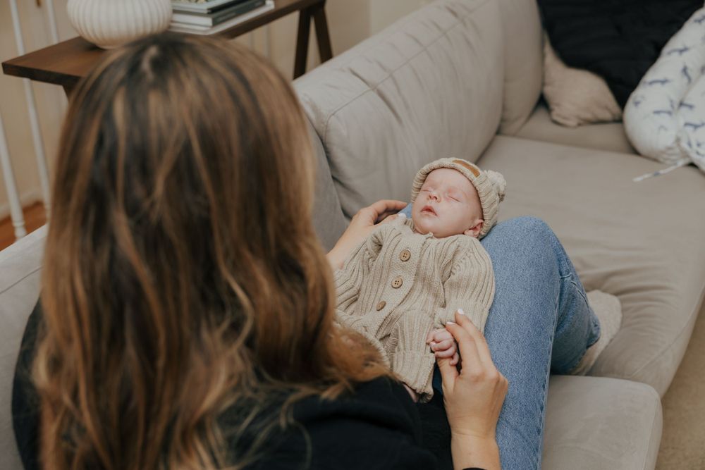 Peaceful moment on couch with small baby wearing cream knit sweater.
