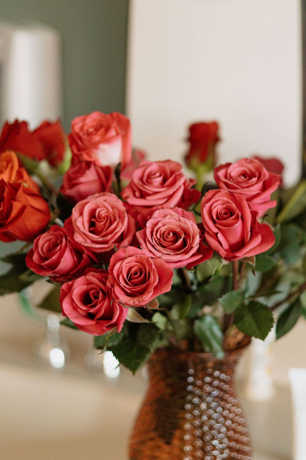 Beautiful arrangement of coral pink roses in a textured brown vase.