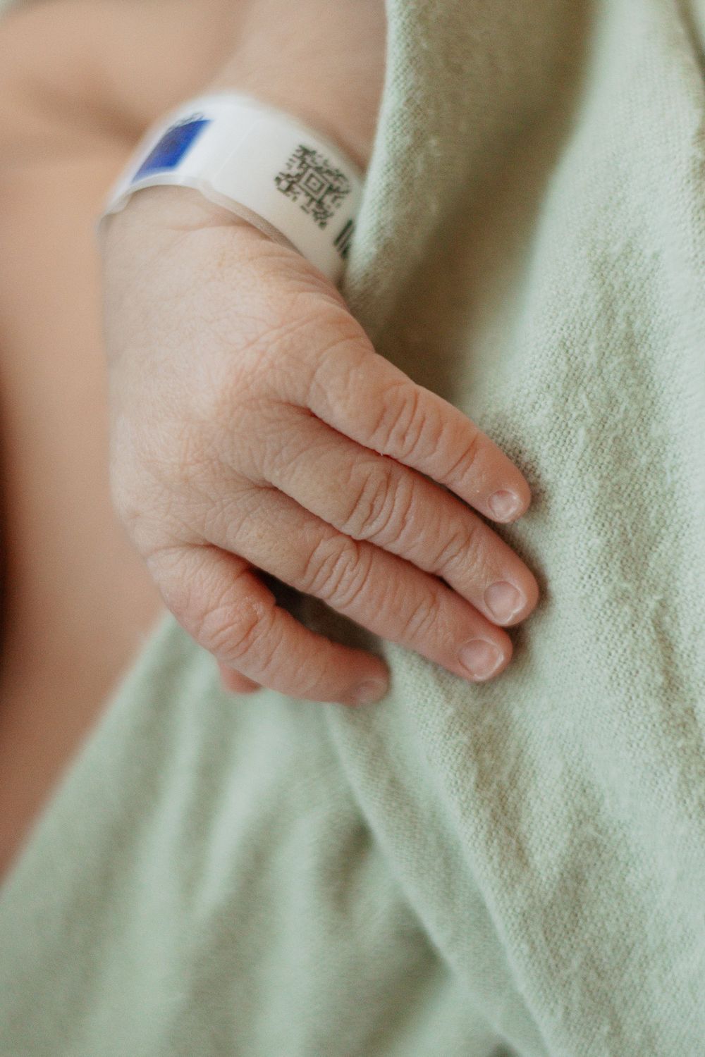 Close-up of newborn baby's tiny hand with hospital identification bracelet.