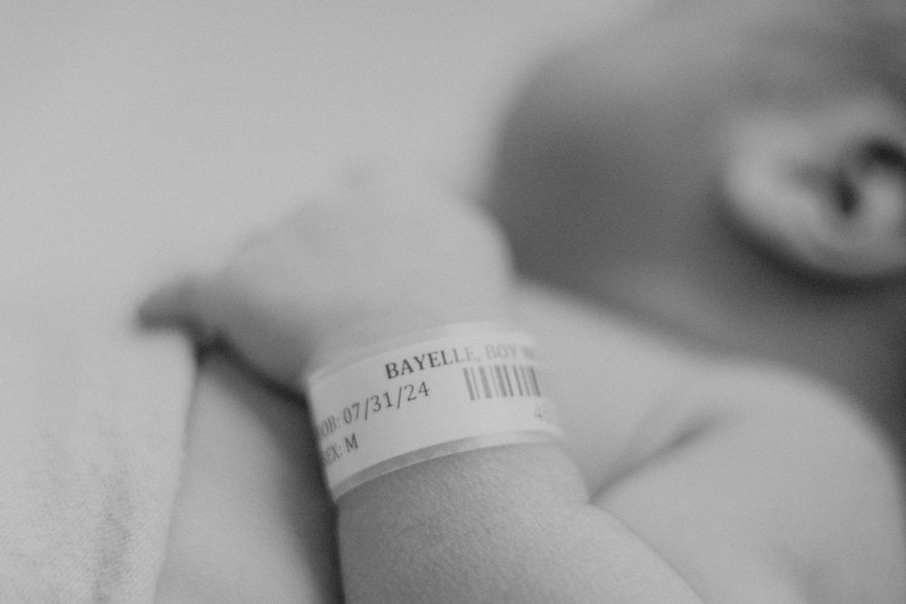 Black and white detail shot of hospital bracelet on sleeping infant.