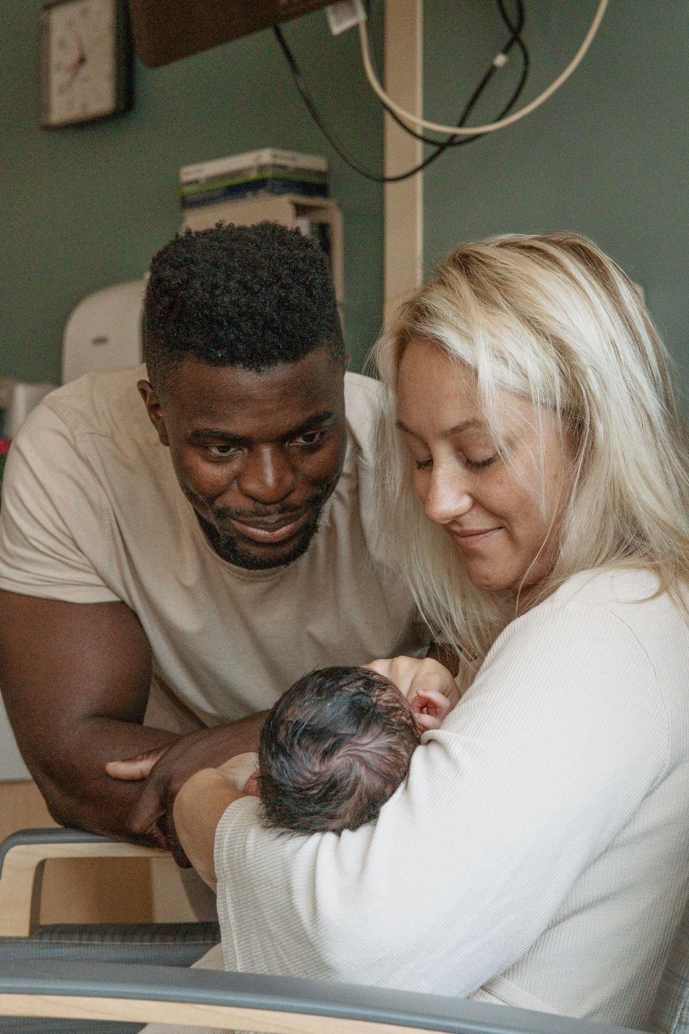 Parents gazing lovingly at their newborn baby during hospital stay.