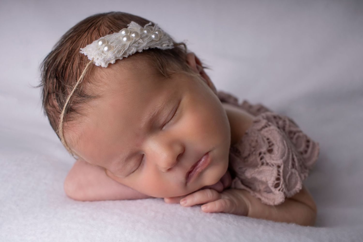 A newborn girl sleeps peacefully with her head rested on her arms