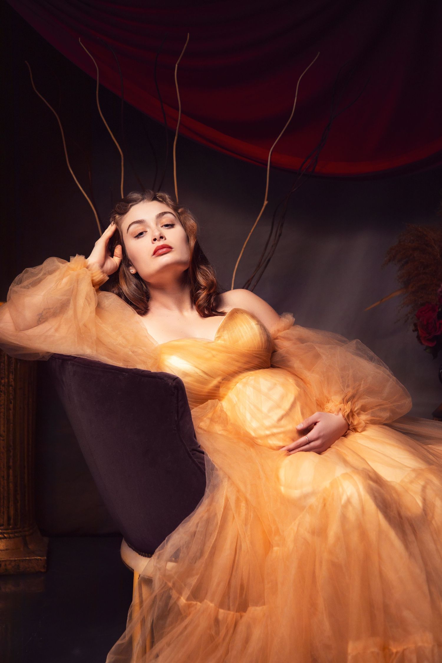 Dramatic portraits in golden tulle gown against dark background with artistic lighting.