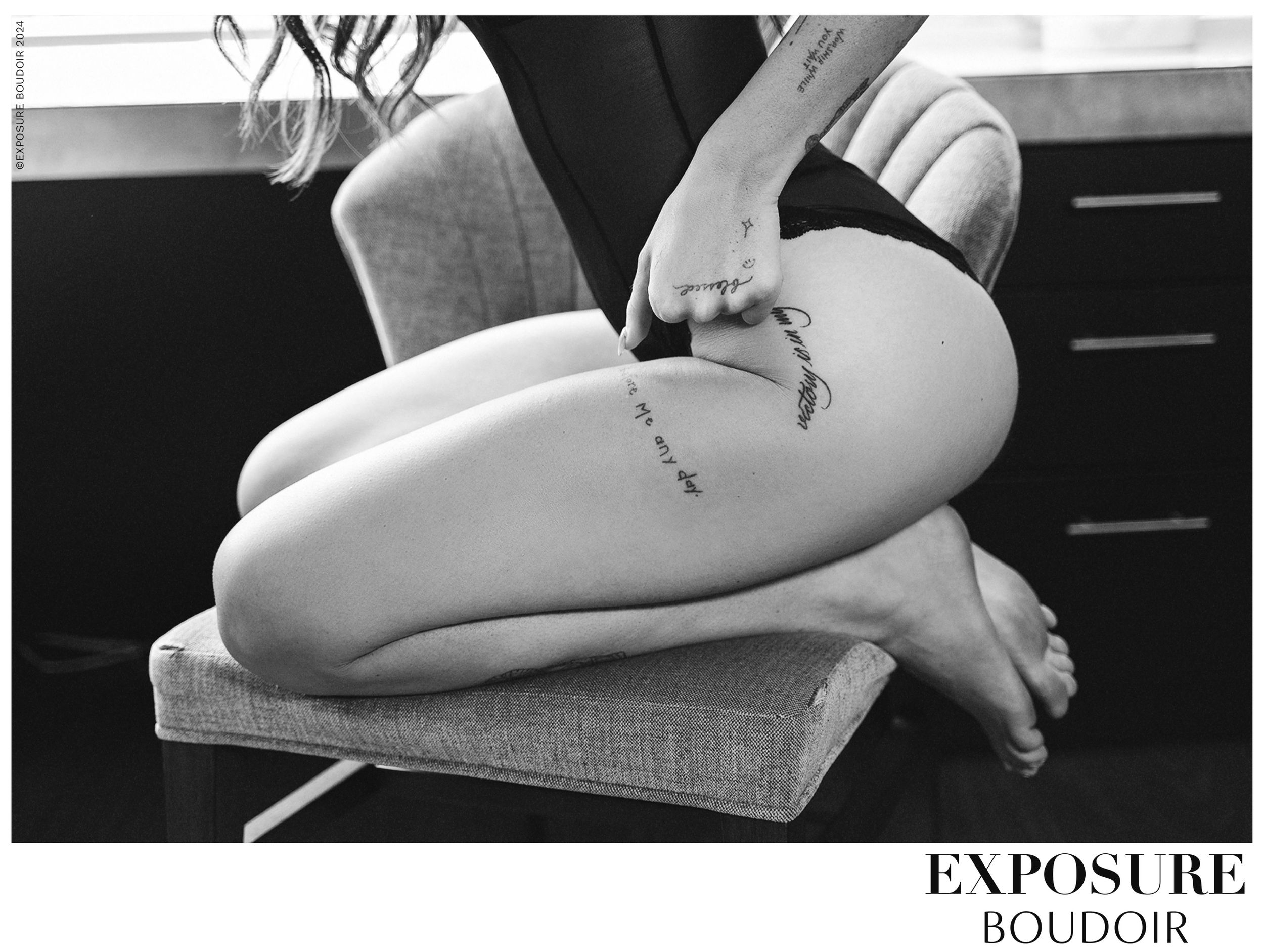 Black and white boudoir photo showing bare legs resting on a textured surface with an artistic lighting effect.