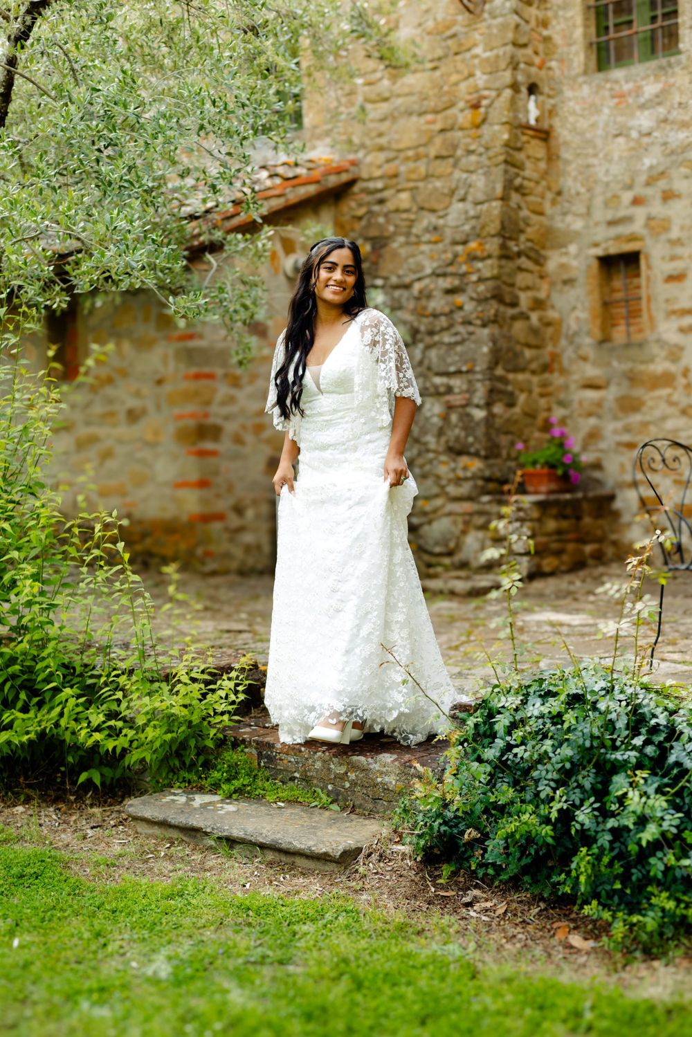 Wedding photos taken against a rustic stone wall with green garden foliage.