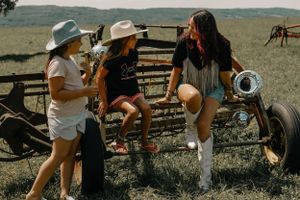 Friends enjoying a summer day hanging out by rustic farm equipment in a field.