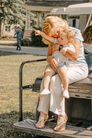 A tender moment shared on a golf cart seat in a sunny outdoor setting.