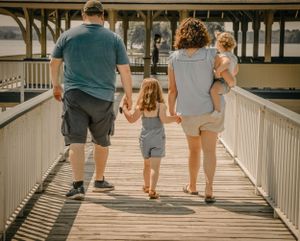 Family walking together on a wooden boardwalk on a sunny afternoon.