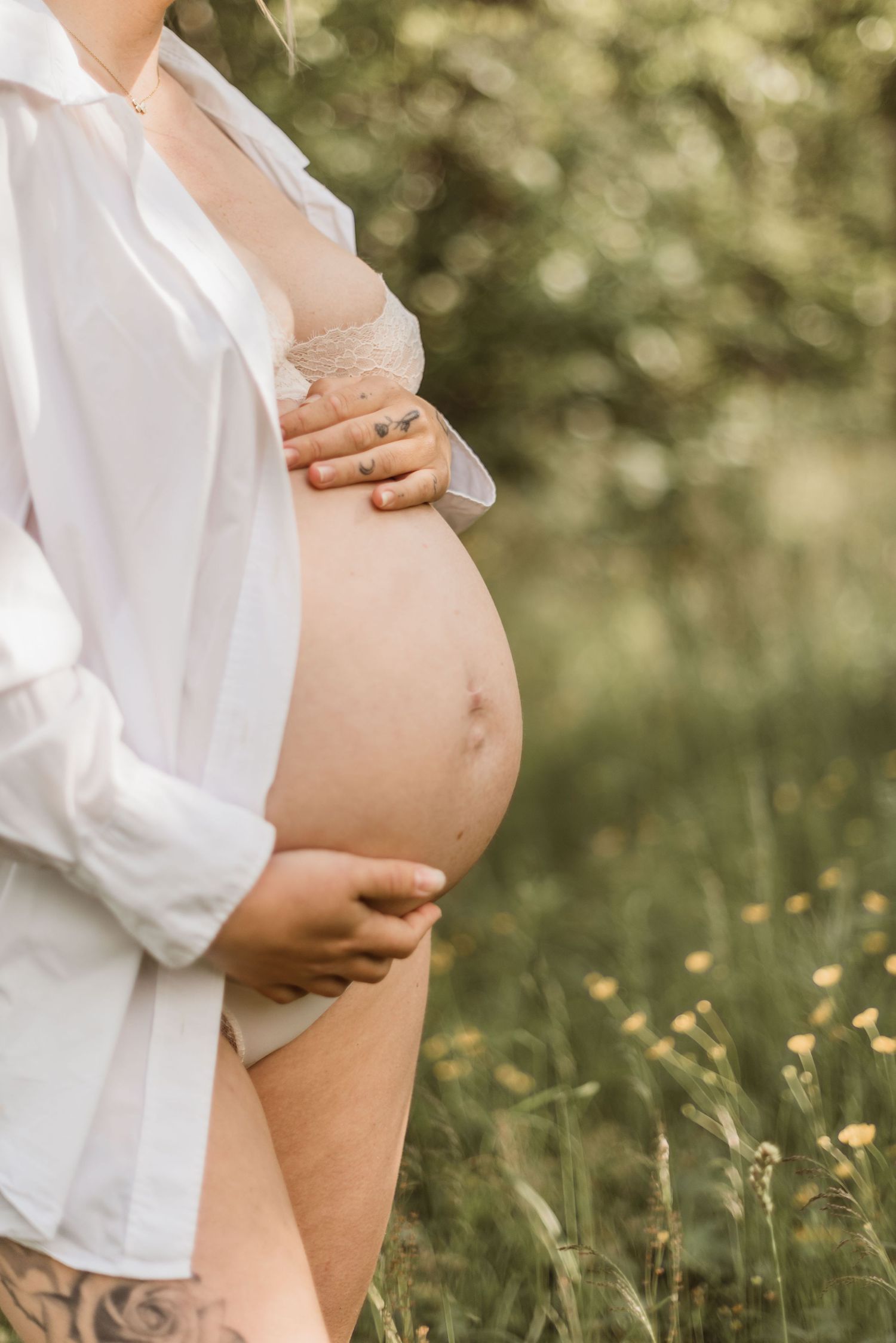 Close-up maternity photograph showing hands cradling baby bump at sunset.