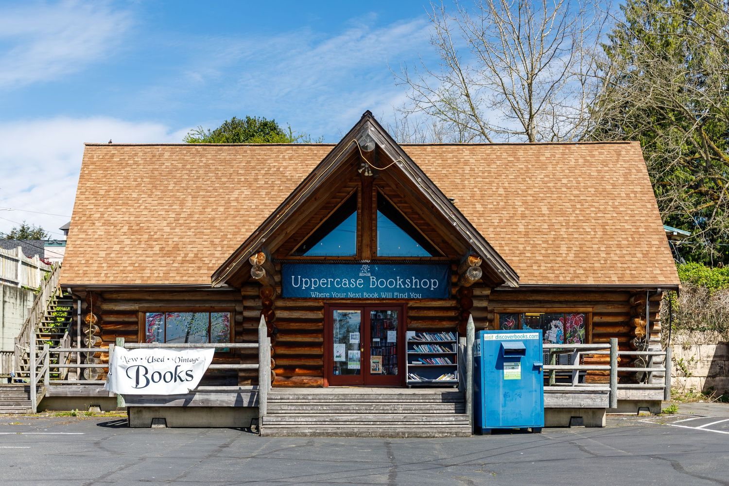 Exterior view of log cabin bookstore with wooden architecture and blue signage.