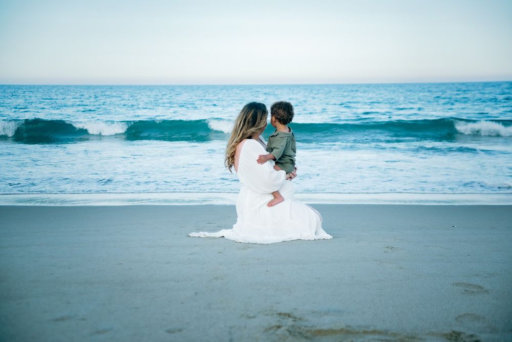 A pregnant mama with her toddler son staring off into the ocean for her Maternity Photoshoot.