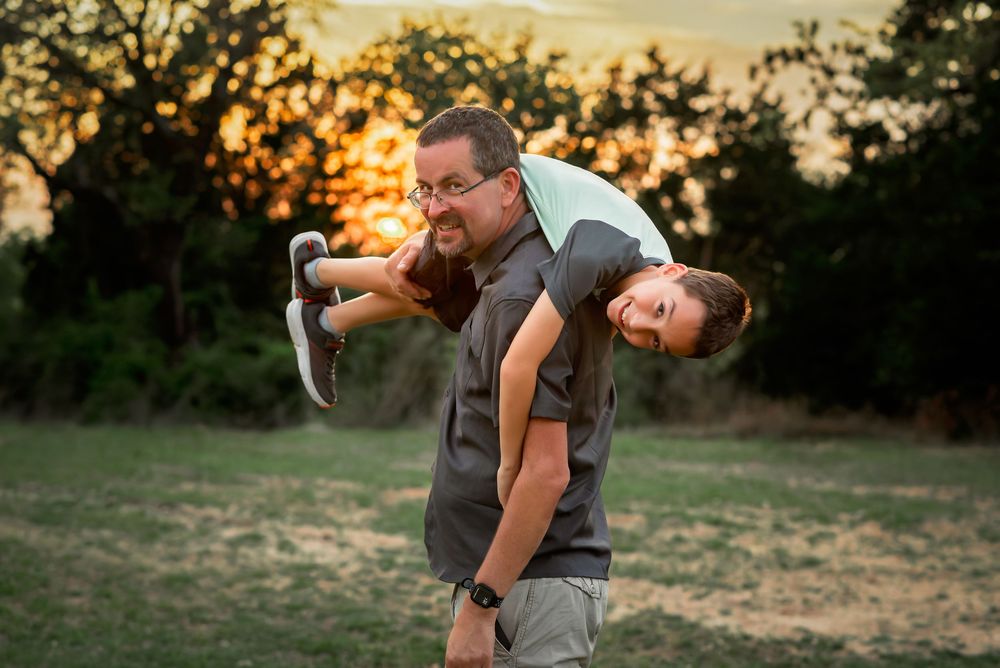 A dad playing with his son where he threw his son over his shoulder for this fun family shot.