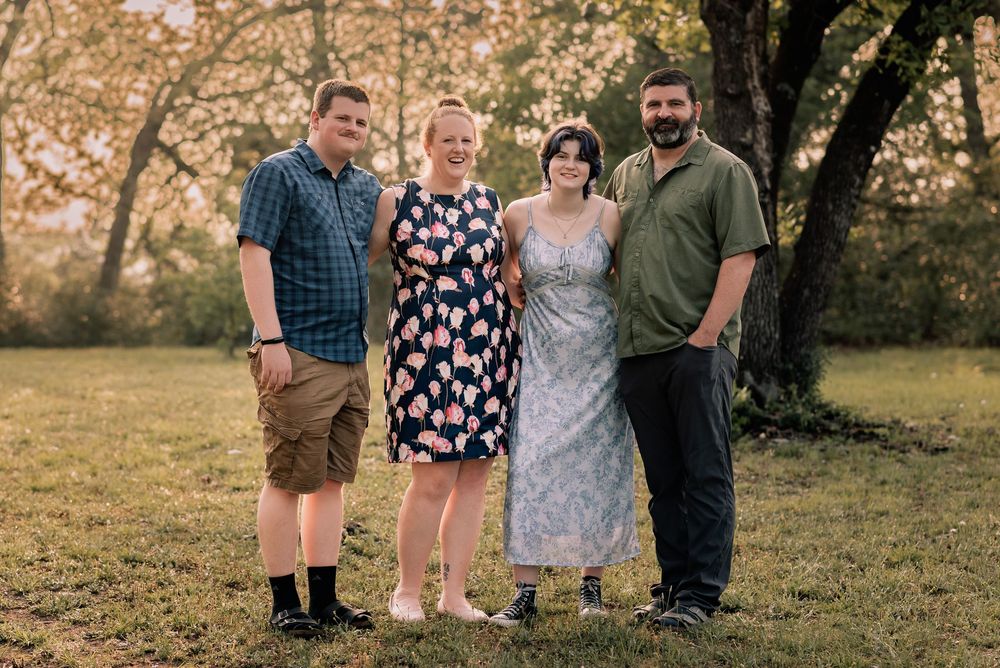 A family of 4 with a boy and girl teenagers standing for their portrait