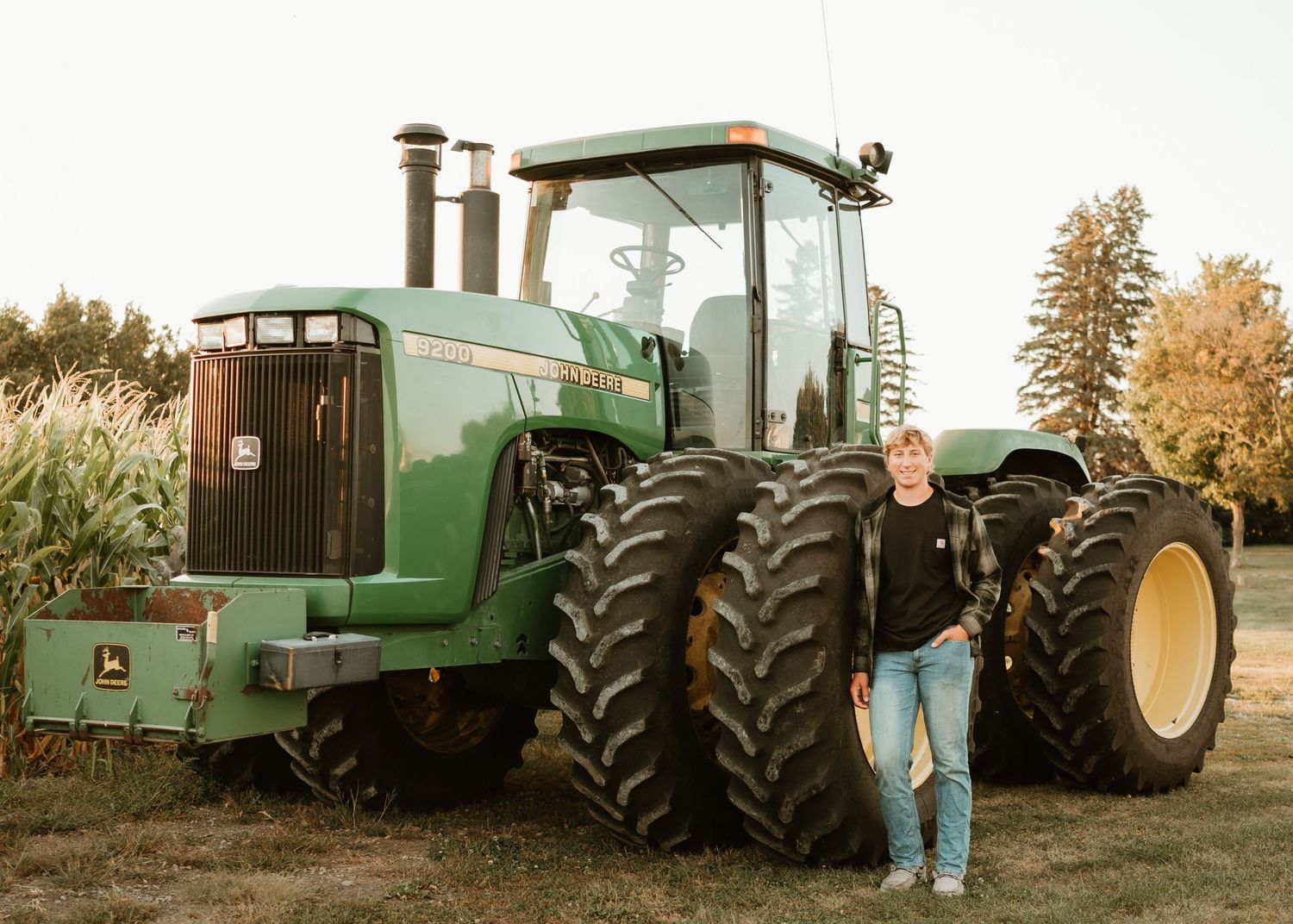 Large green John Deere tractor with person standing beside for scale.
