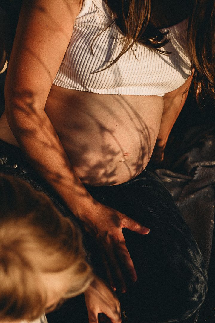 Artistic close-up shot of torso in striped top with sunlit shadows.