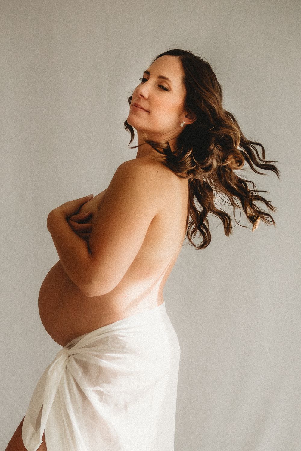 Artistic maternity photos in white fabric showing movement and grace.