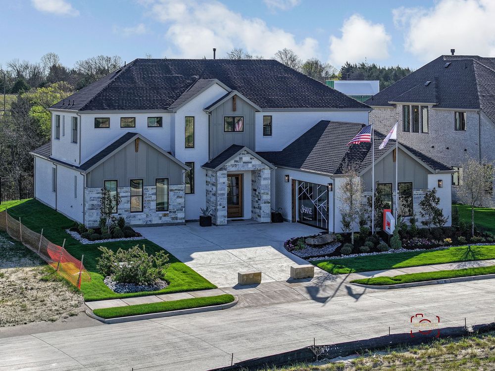 Aerial panoramic view of modern suburban homes with well-maintained lawns and driveways in a residential neighborhood.