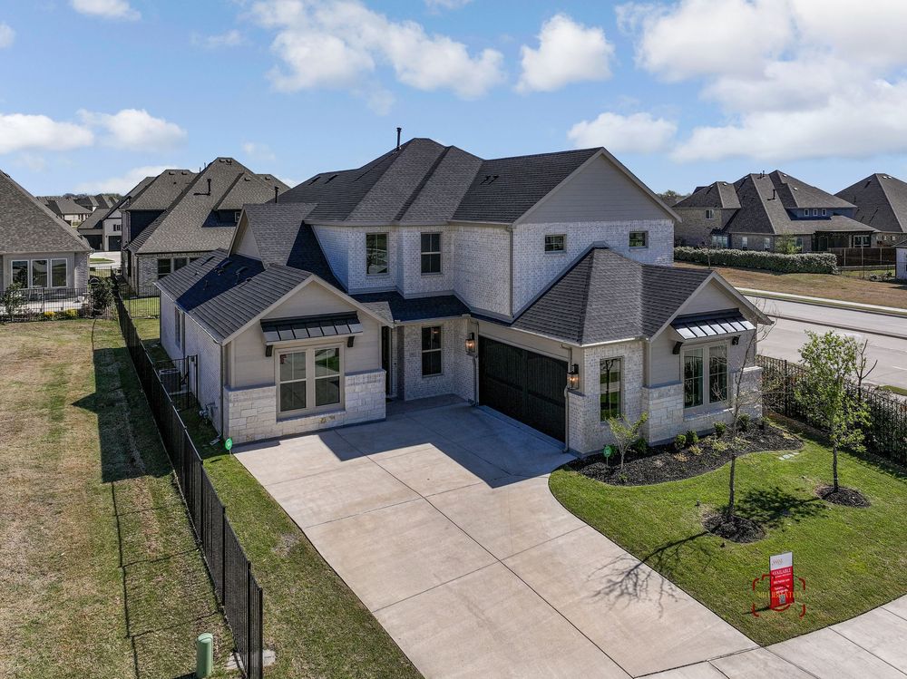 Aerial view of a modern two-story white house with dark gray roof and concrete driveway in a suburban neighborhood.