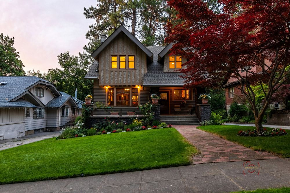 A series of residential homes with illuminated windows at dusk showcasing beautiful landscaping and architectural details.