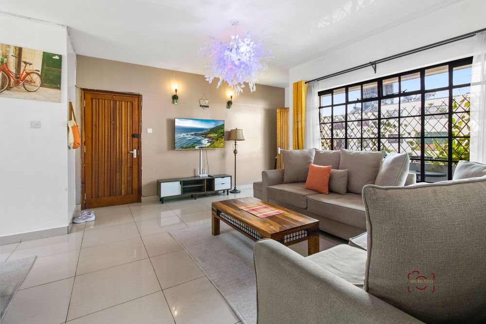 Modern apartment interior showcases bright living spaces with large windows and contemporary gray furniture.