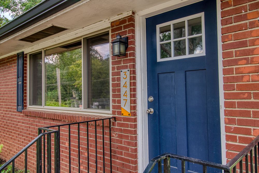 Red brick house exterior with navy blue front door and white trim details features classic architectural elements.
