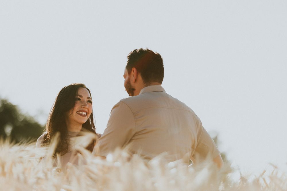 Couple sharing a joyful moment together in a golden wheat field at sunset.