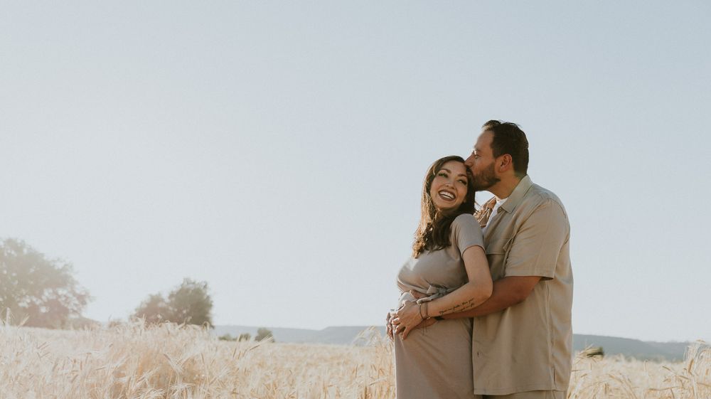 A sunset maternity photo showing an intimate moment between a couple.