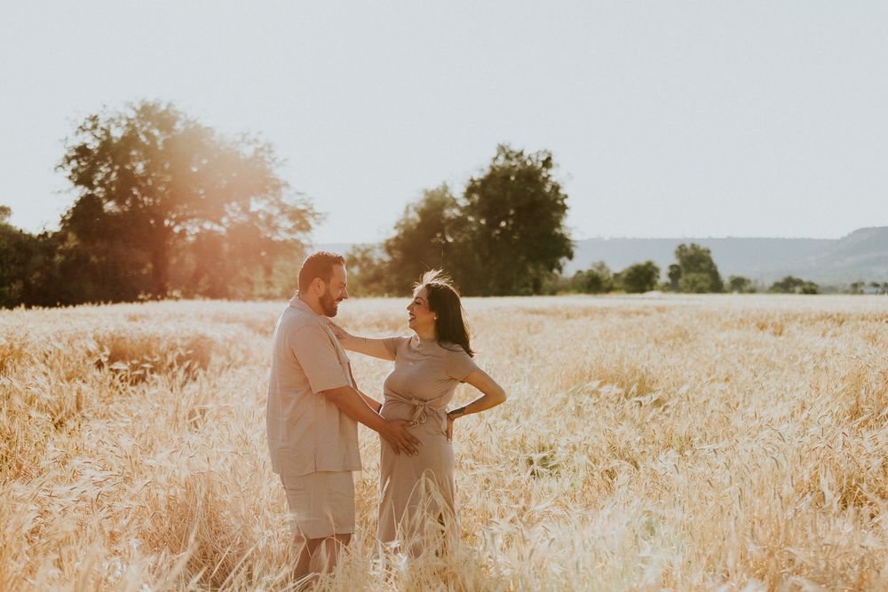 Couple dances in sunlit wheat field during golden hour.