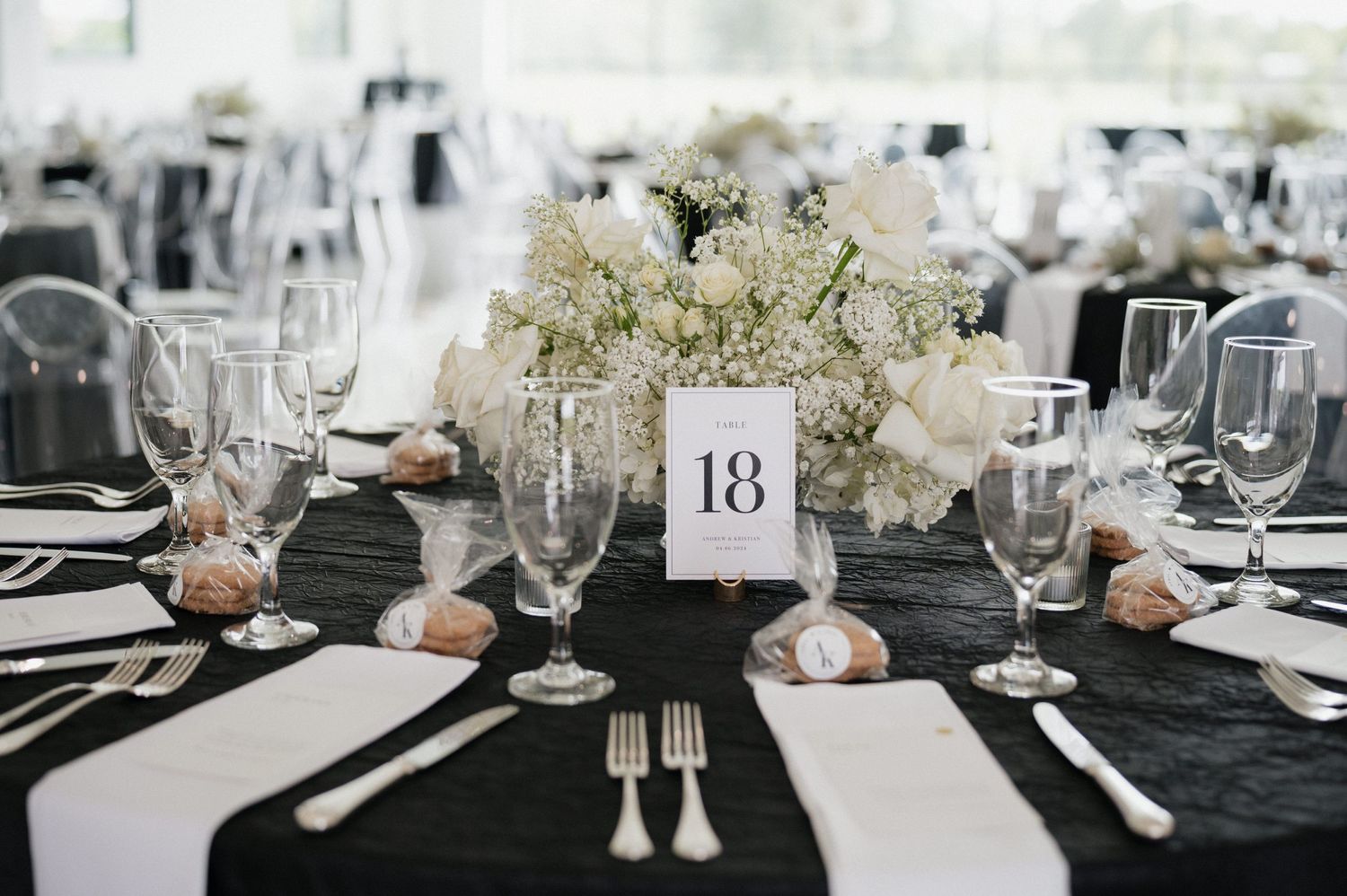 Elegant wedding table setting with black linens, white hydrangea centerpiece, and table number thirteen displayed.