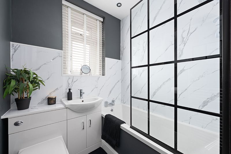 Modern bathroom interior with black framed windows, white marble walls, and minimalist fixtures creating a sleek design.