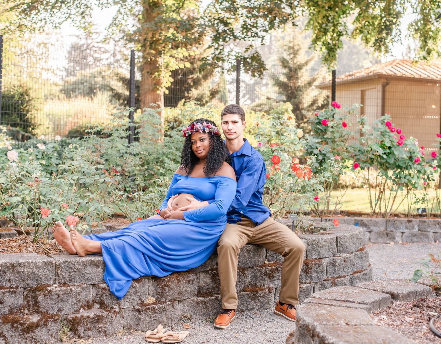 Couple in matching blue and tan outfits pose together in rose garden setting.