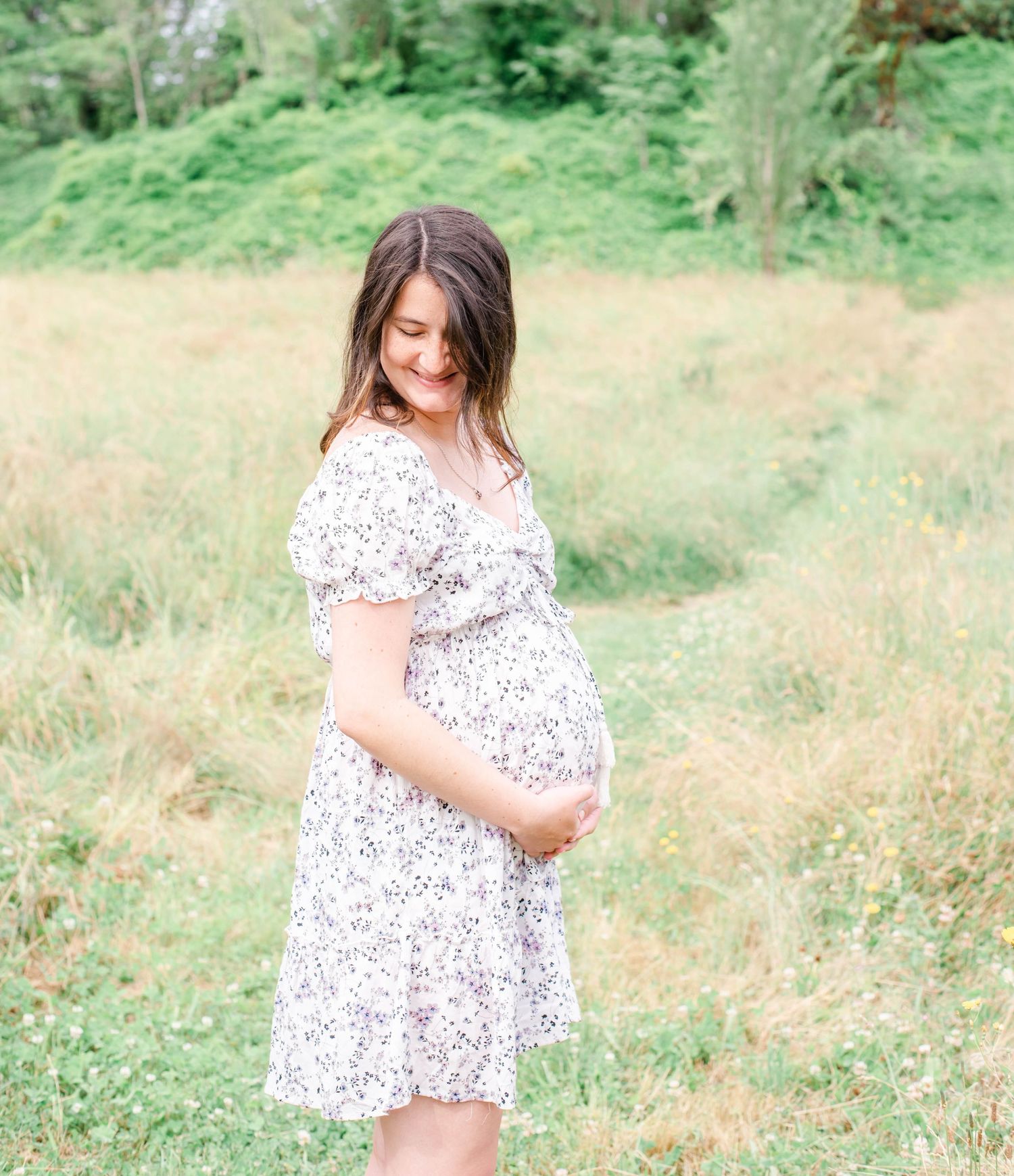 Natural light photography session in a wildflower meadow with green trees in background.