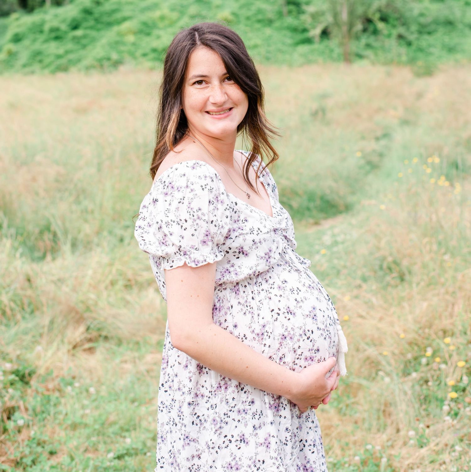 Beautiful outdoor maternity session featuring a flowing white floral dress in nature.