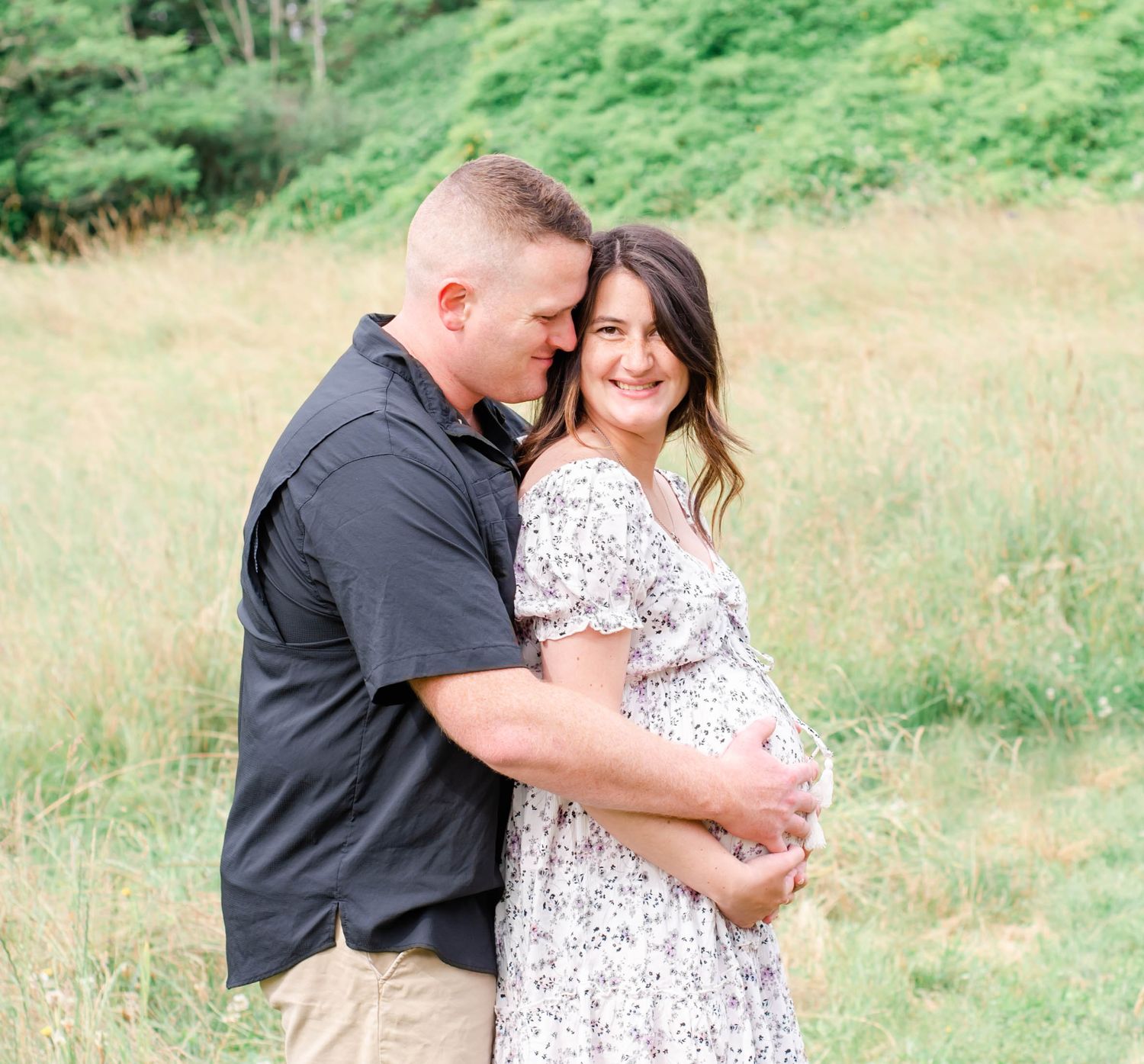 Sweet maternity photos of expecting couple embracing in a sunlit field.