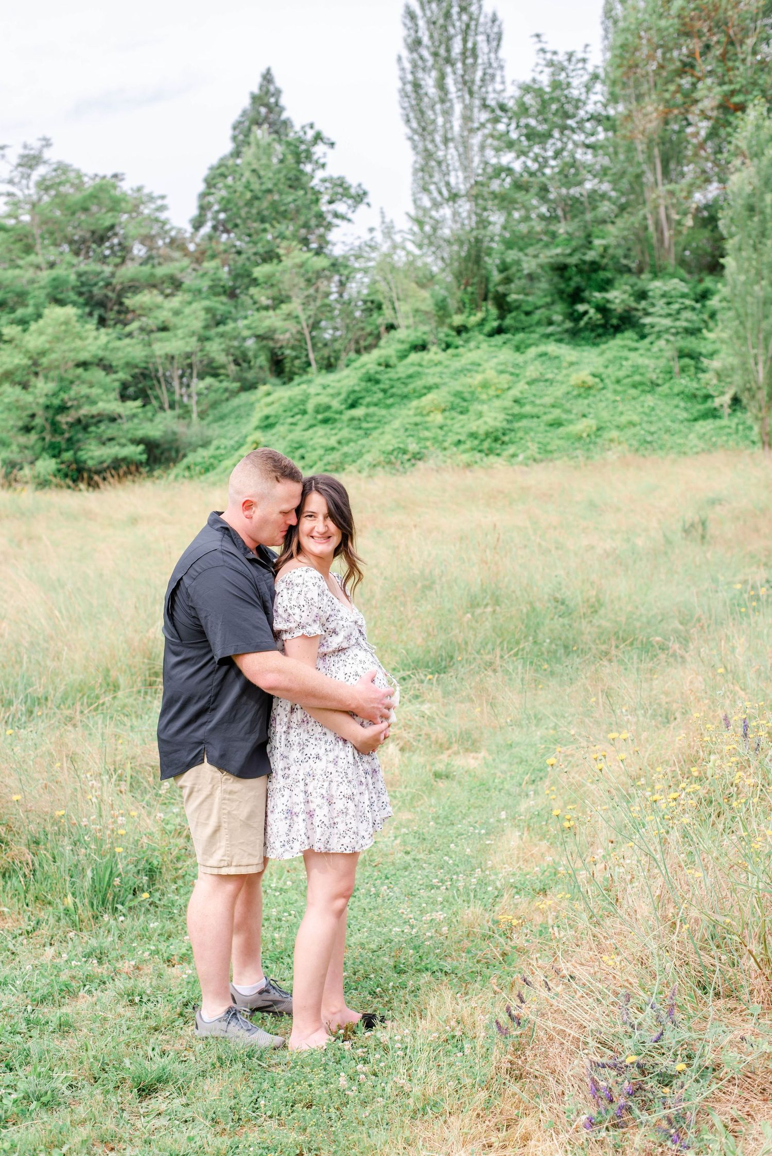 Intimate maternity photography session in a summer meadow with golden light.